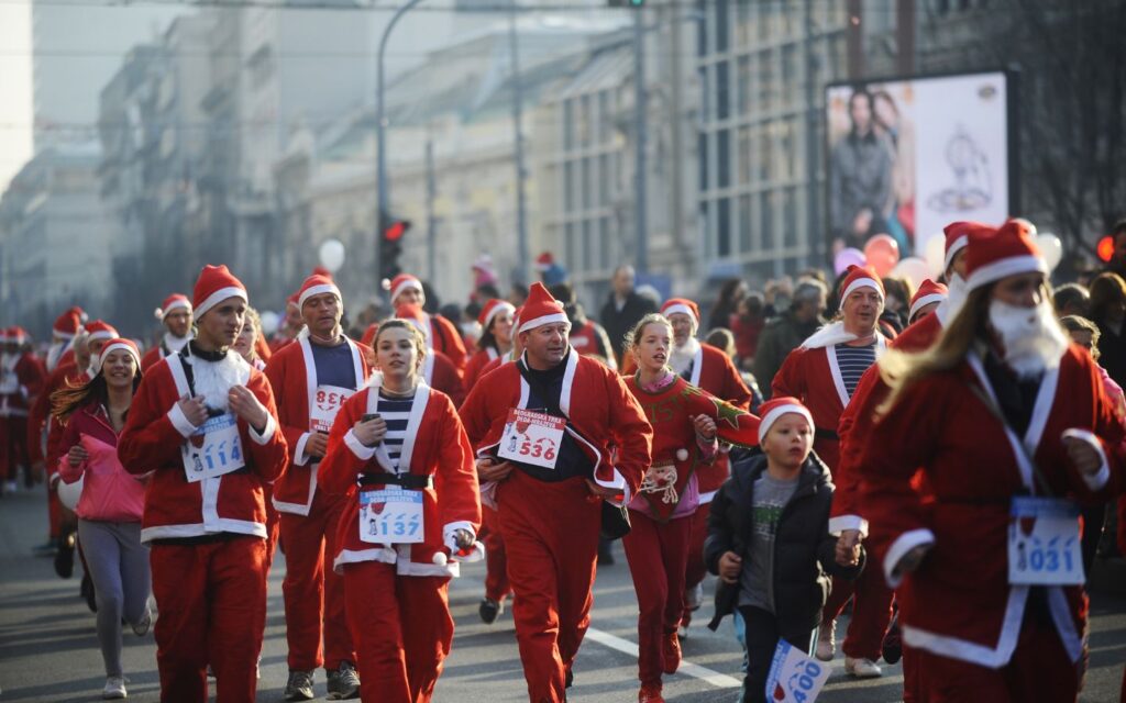Families in Santa costumes running together at Dubai Santa Run 2025 on West Beach