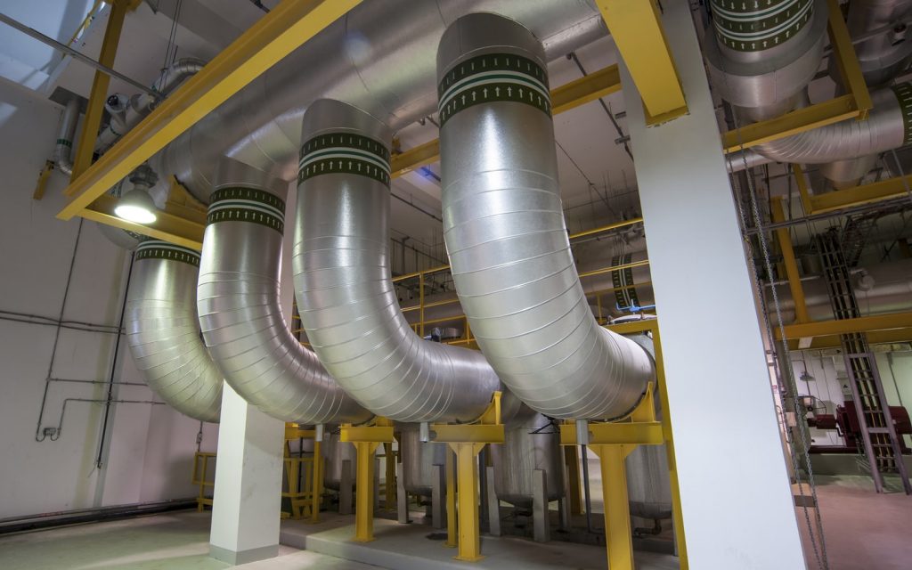 Inside a district cooling plant showing large insulated pipes and pumps